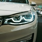 L'avant d'une voiture blanche dans une salle d'exposition, phares allumés