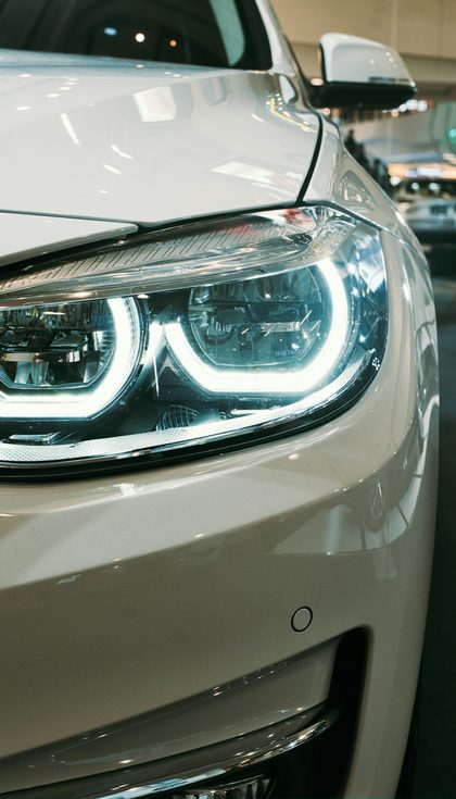 L'avant d'une voiture blanche dans une salle d'exposition, phares allumés
